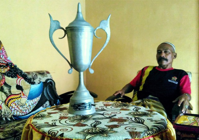 Piala: Pak Pamrih sedang duduk santai di rumahnya, ditemani piala penghargaan saat mementaskan turangga yaksa pertama kali | Foto Mas Trigus